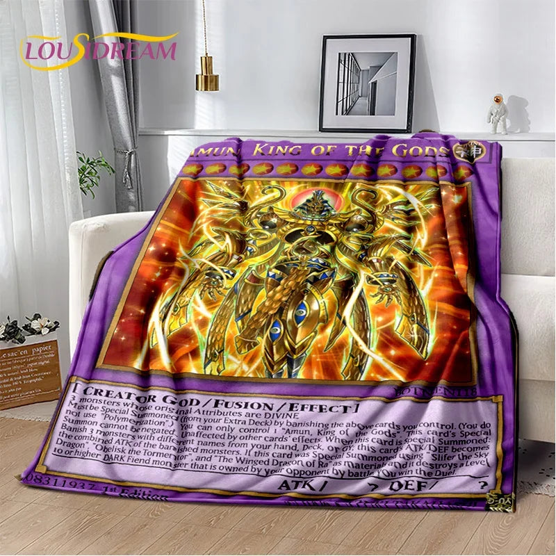 A plush throw blanket featuring a Yu-Gi-Oh! card game style design with the 'King of the Gods' card artwork, draped over a white sofa in a living room setting.