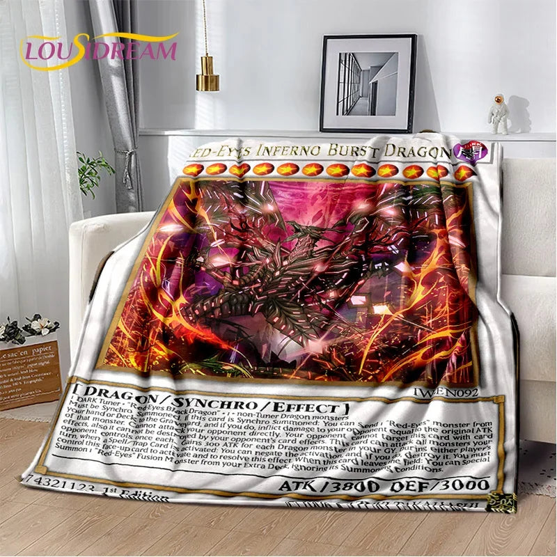 A Udon-branded throw blanket featuring a detailed Yu-Gi-Oh! card design with the '2D-Eyes Inferno Burst Dragon' card, draped over a white armchair in a modern living room setting.