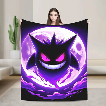 A woman holds up a large black blanket or tapestry featuring a stylized purple and pink cartoon ghost character in front of a glowing moon, shown in a modern living room setting.