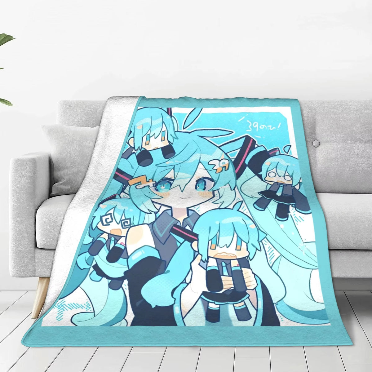 A soft throw blanket with a light blue and white plush fleece backing, featuring a printed anime-style illustration of multiple Hatsune Miku characters, styled on a light gray sofa.