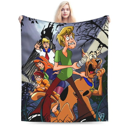 A person holding up a large printed blanket or tapestry featuring the Scooby-Doo cartoon characters against a dark spooky forest scene, photographed on a plain white background.