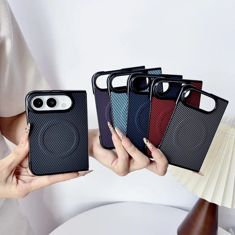 A person holds several slim phone cases with a circular magnetic ring design. The front case is black with a carbon-fiber-style texture, and the cases behind it show additional color options including dark blue, light blue, dark red, and dark gray with diagonal stripes.