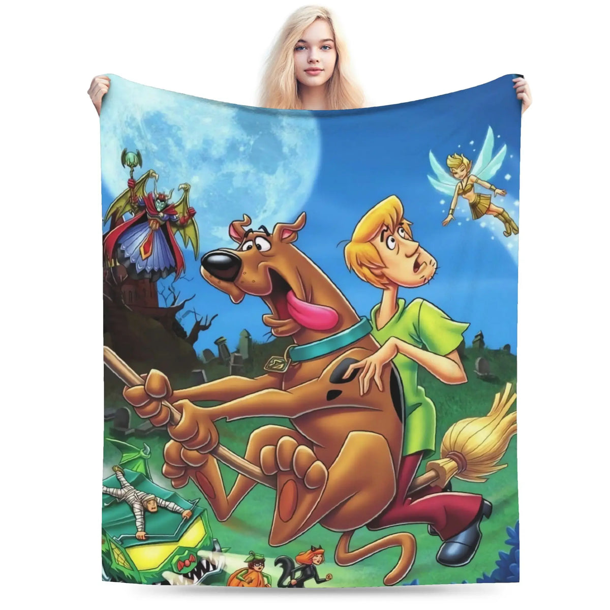 A person holds up a large printed blanket or tapestry featuring cartoon characters from Scooby-Doo, including Scooby-Doo, Shag, and a fairy, against a plain white background.