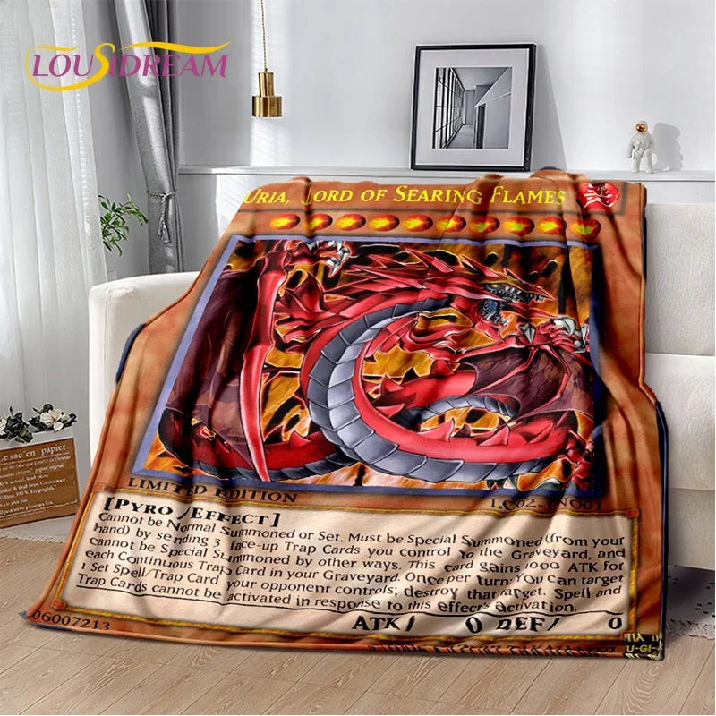 A printed throw blanket draped over a white sofa in a living room, featuring a red dragon artwork styled like a Pokémon battle card with text boxes and a gold border.