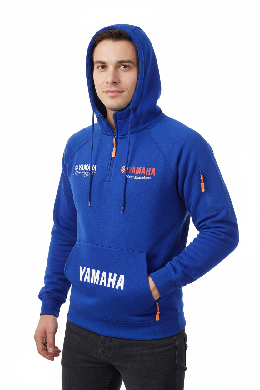 A man wearing a royal blue Yamaha branded pullover hoodie with white and red logo graphics, standing against a plain white studio background.