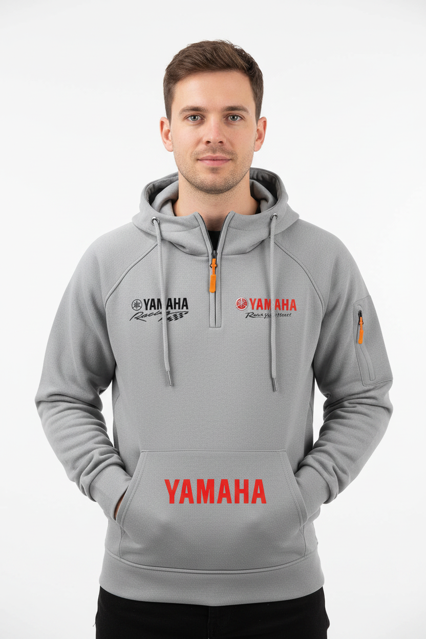 A man wearing a light gray Yamaha hoodie with red and black logo graphics on the chest and front pocket, photographed against a clean white studio background.