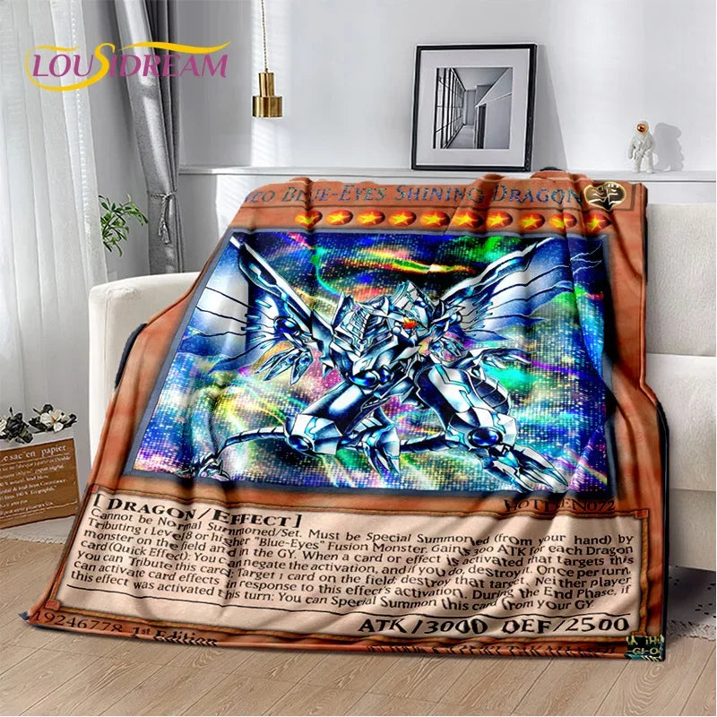 A plush throw blanket featuring a colorful Yu-Gi-Oh! dragon illustration and card-style text, draped over a white armchair in a living room setting.