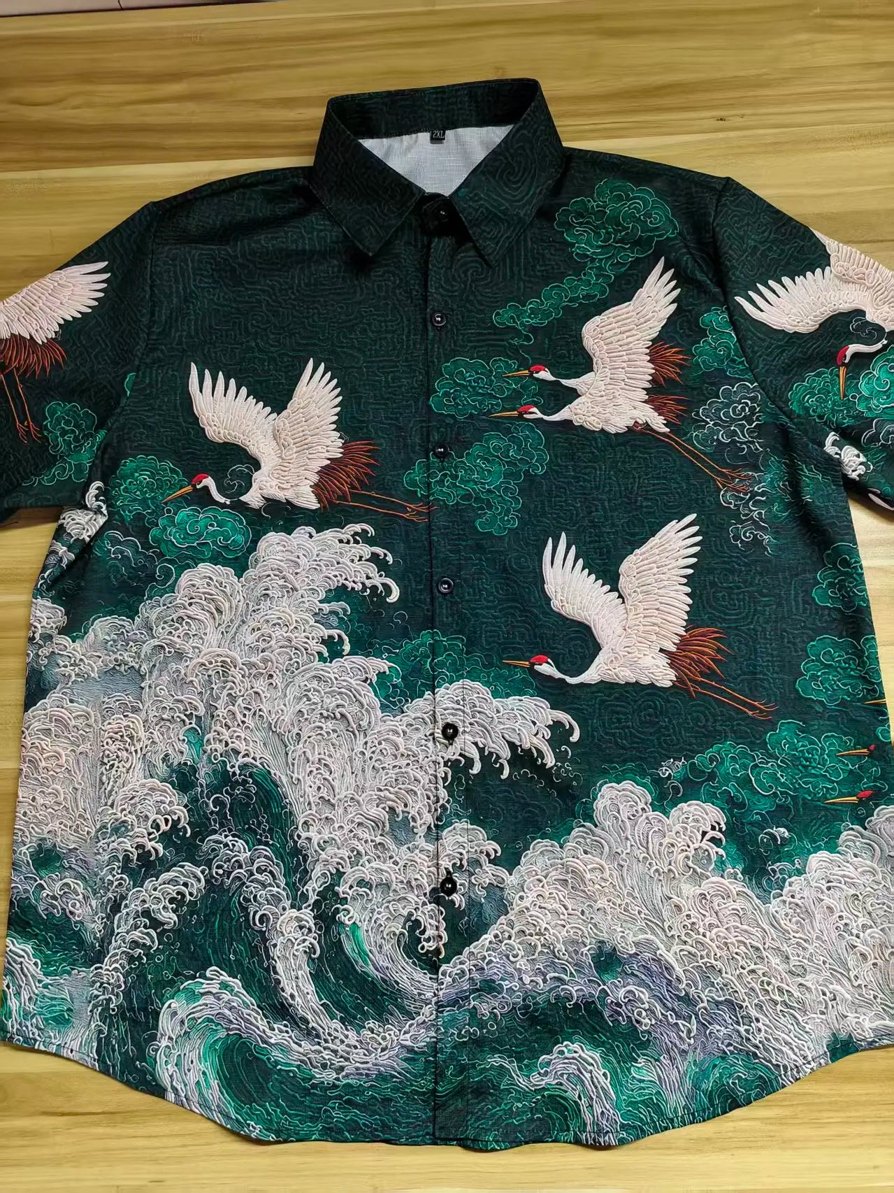 Embroidered shirt with crane designs on a wooden surface
