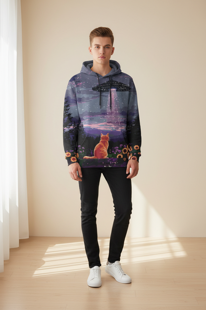 A man modeling a dark purple and black pullover hoodie with a colorful graphic print of a cat in a field under a UFO, paired with black pants and white sneakers, standing in a brightly lit room.