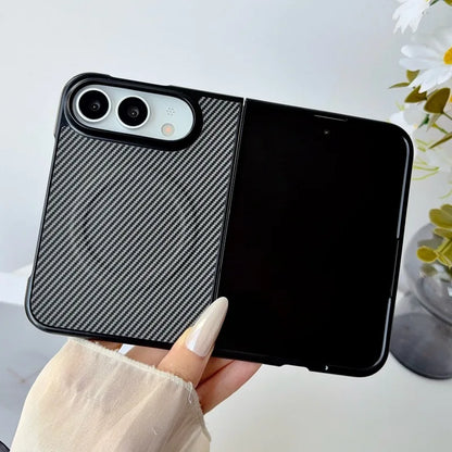 A black phone case with a carbon fiber textured back panel and a solid black back cover, held by a hand with long white manicured nails.