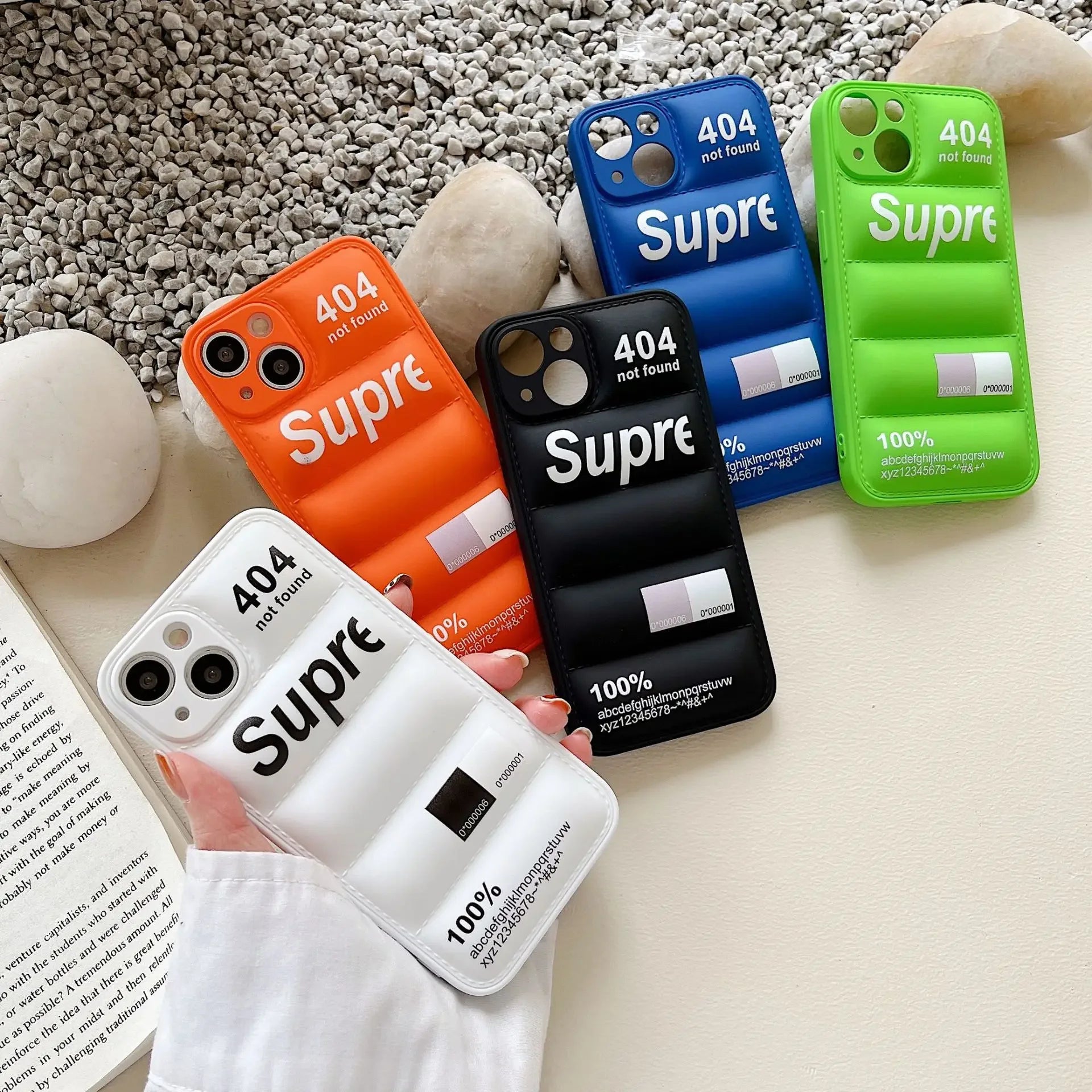 Five phone cases with 'Supreme' branding on a textured surface.