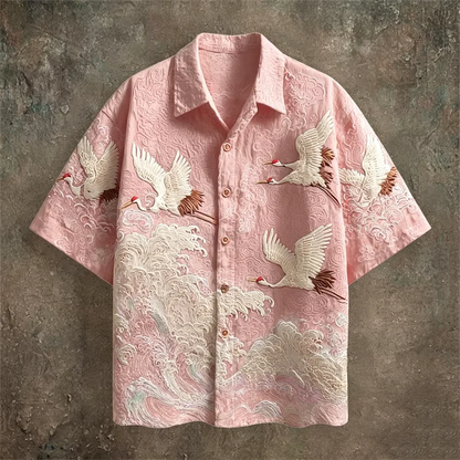Pink shirt with crane embroidery on a textured brown background