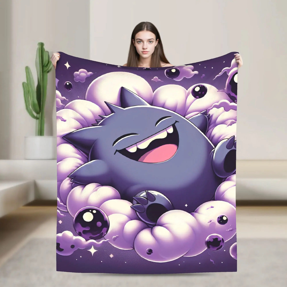 A woman holds up a large blanket or tapestry featuring a cartoon purple creature surrounded by purple and white cloud-like shapes on a dark background. The room behind her is softly lit, with a cactus visible on the left.
