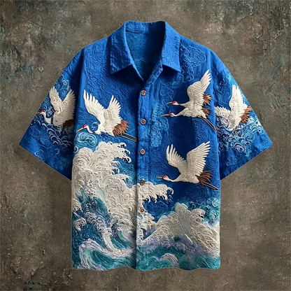 Blue embroidered shirt with crane designs on a textured brown background