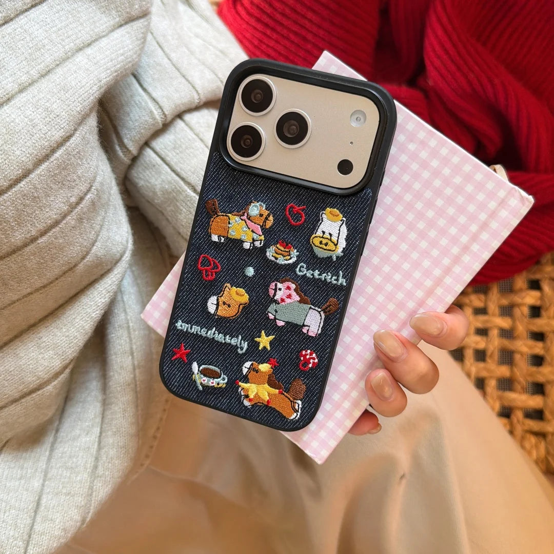 Phone case with embroidered designs held by a person on a pink checkered surface