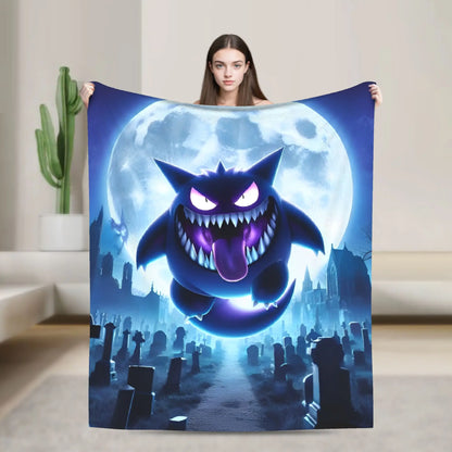A woman holds up a large blanket featuring a spooky cartoon monster in front of a full moon over a graveyard, shown in a modern living room setting.