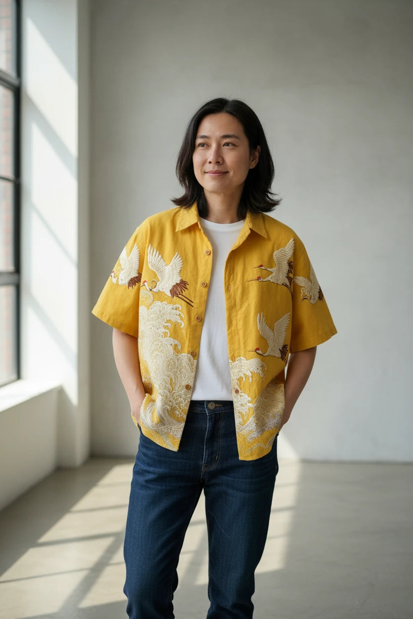 Yellow shirt with crane embroidery on a textured brown background