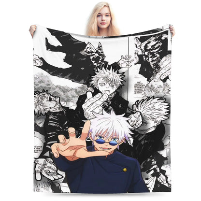 A person holds up a large square blanket or throw featuring a black-and-white manga collage with anime characters in the foreground. The person is partially visible behind the blanket, and the background is a clean white studio backdrop.