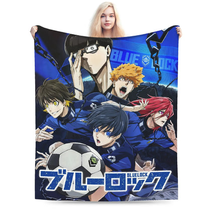 A person holds up a large printed blanket or throw featuring anime characters from Blue Lock, including a soccer ball graphic and the Blue Lock logo, against a plain white background.