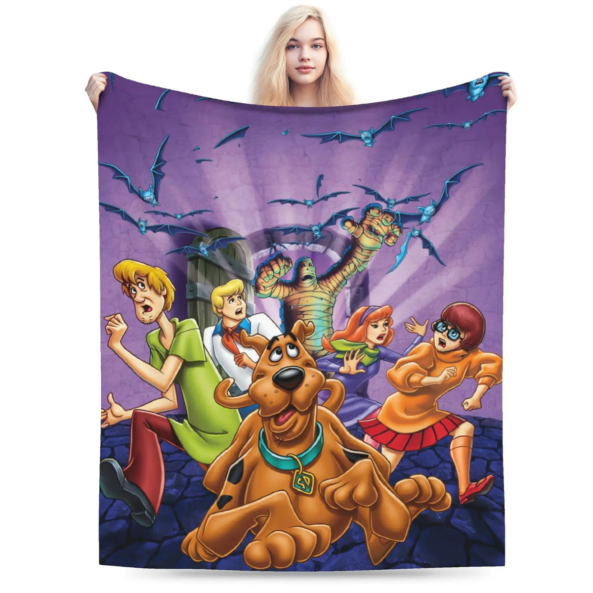 A large printed blanket or tapestry featuring the Scooby-Doo characters in a spooky scene, held up by a woman against a plain white background.