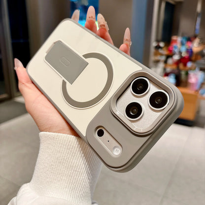 A hand holding a light beige and gray magnetic ring phone case with a triple-camera cutout, set against a blurred indoor background.