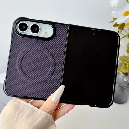 A hand holds a black foldable phone case with a textured dark purple carbon-fiber-style back panel and a black magnetic inner cover, shown against a softly blurred indoor background with flowers.