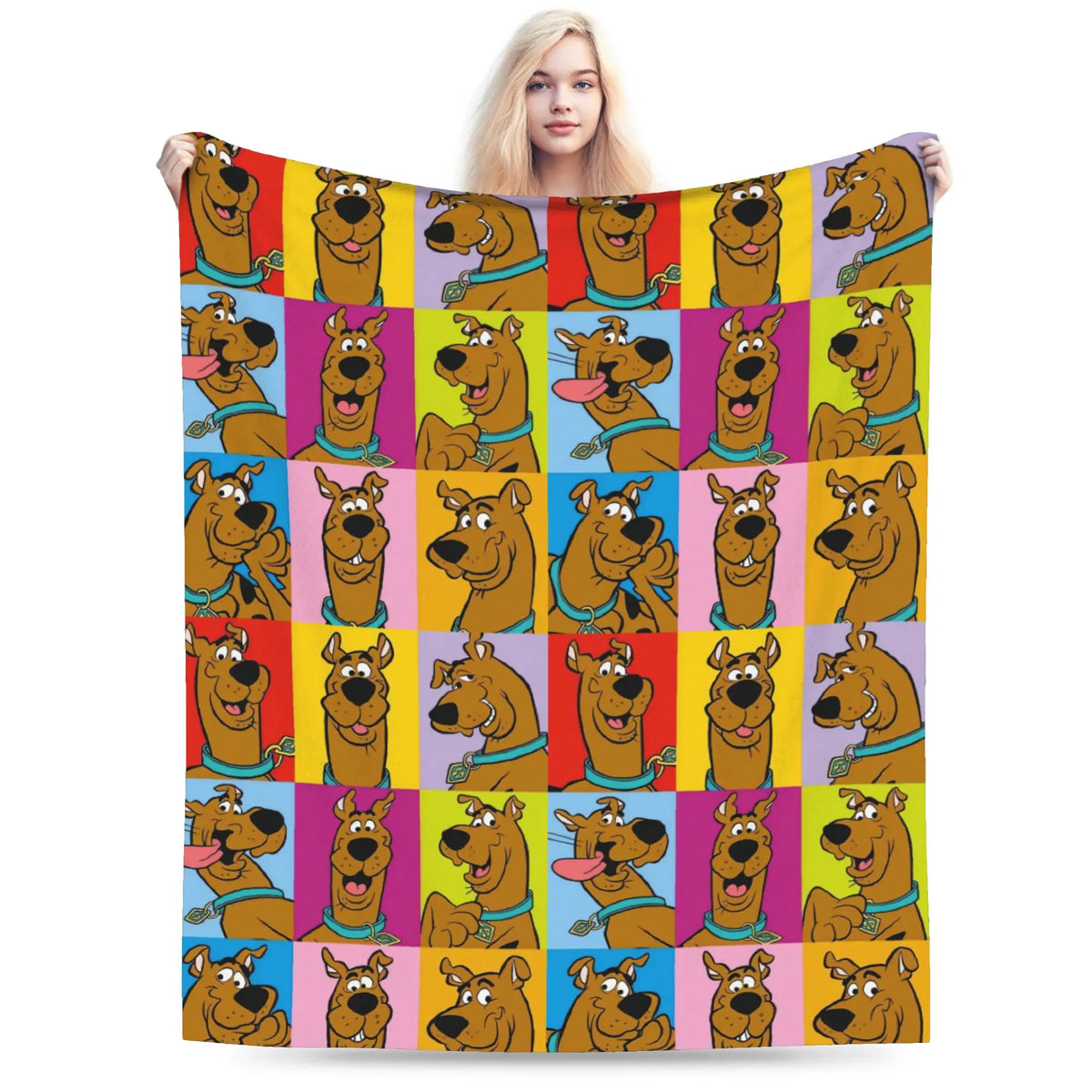 A person holds up a large blanket featuring a colorful grid pattern of Scooby-Doo cartoon faces on a plain white background.