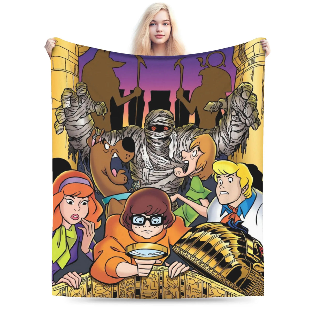 A fleece blanket featuring a colorful cartoon illustration of Scooby-Doo characters, held up by a woman against a plain white background.