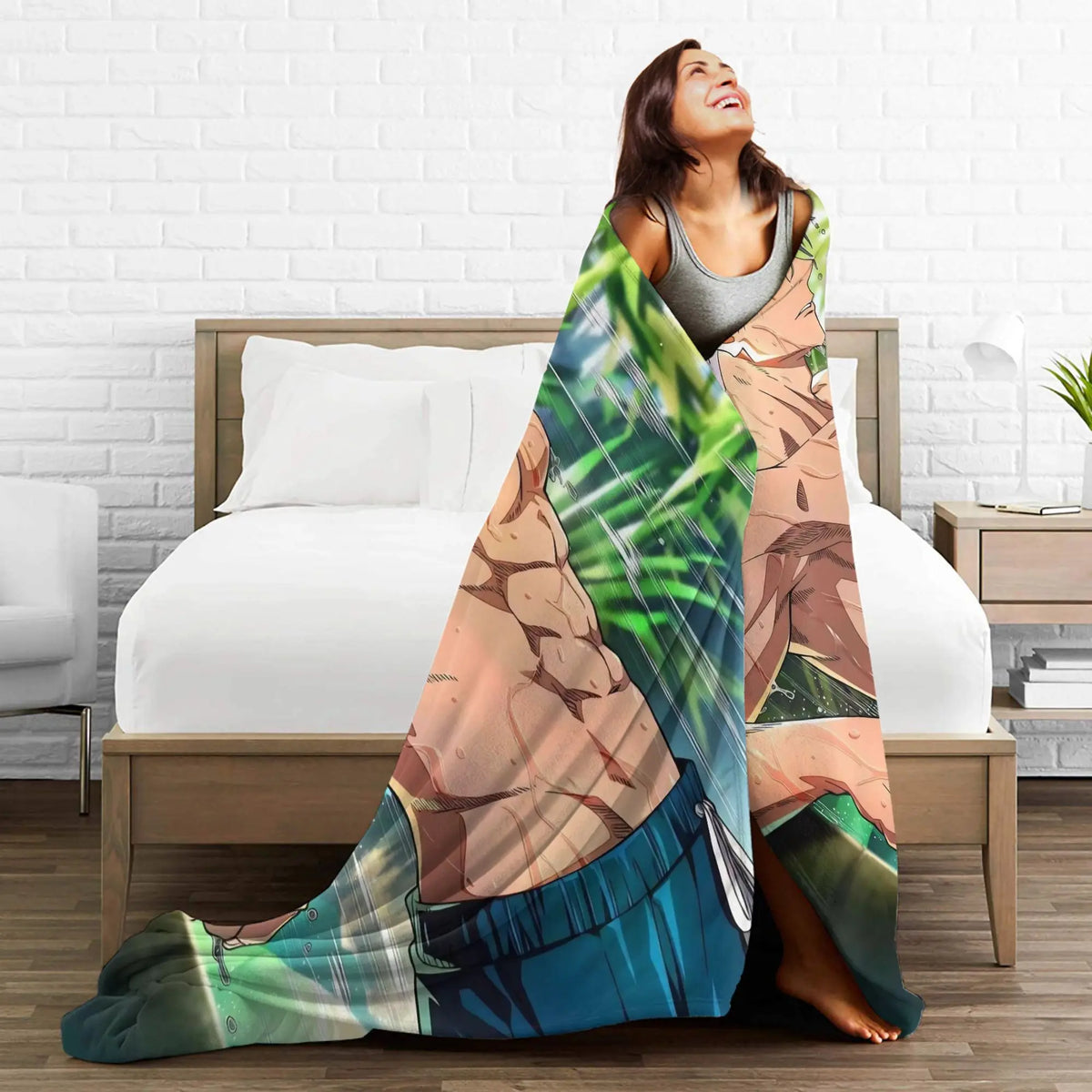 A woman wrapped in a large printed blanket featuring an anime-style muscular male character, standing in a bedroom in front of a bed.