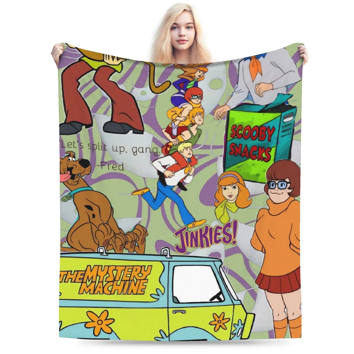 A woman holds up a large fleece blanket featuring a colorful cartoon collage of The Mystery of the Flying Scooby-Doo. The blanket displays characters like Scooby, Fred, Shag, and Velma, the Mystery Machine, and 'Scooby Snacks' on a purple and green patterned background.