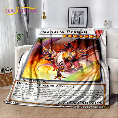 A plush throw blanket featuring a printed Yu-Gi-Oh! 'Dragalia Pyrrah' card design, draped over a white sofa in a living room setting.