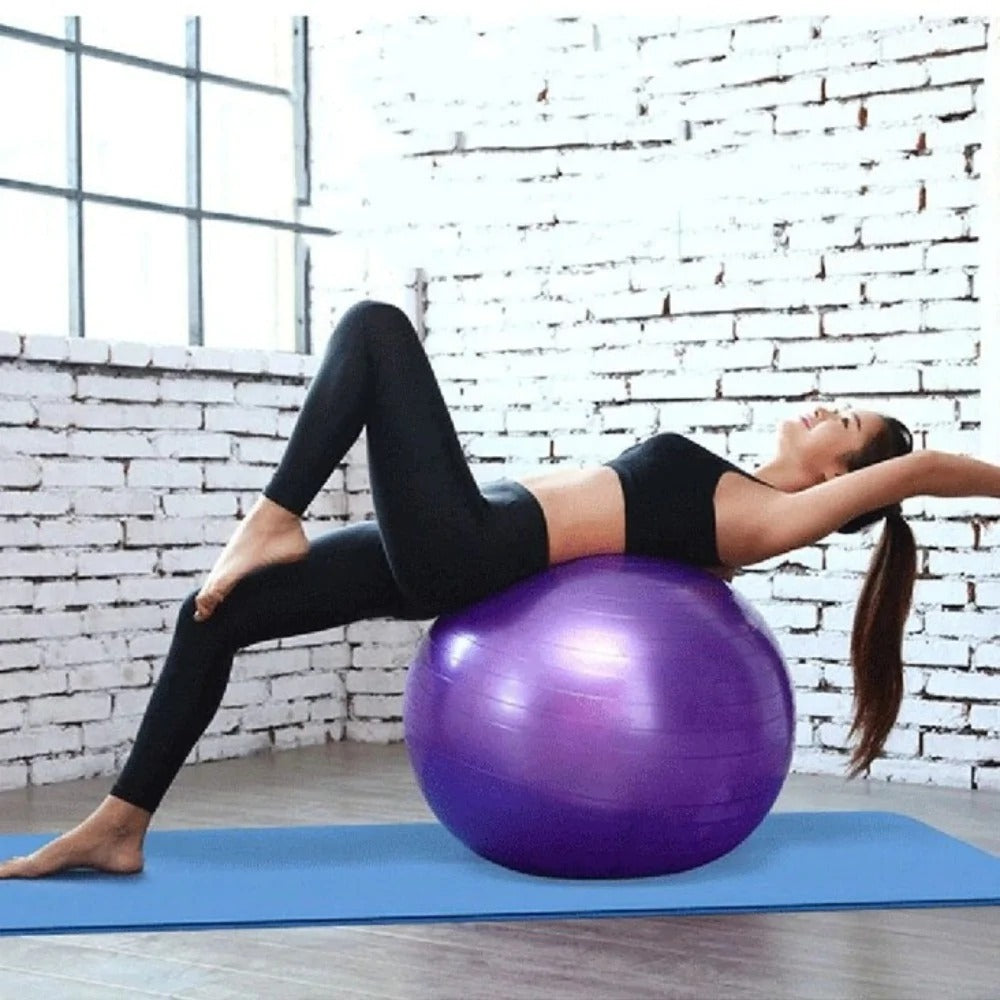 Woman performing exercises on a purple home exercise yoga ball in a bright studio