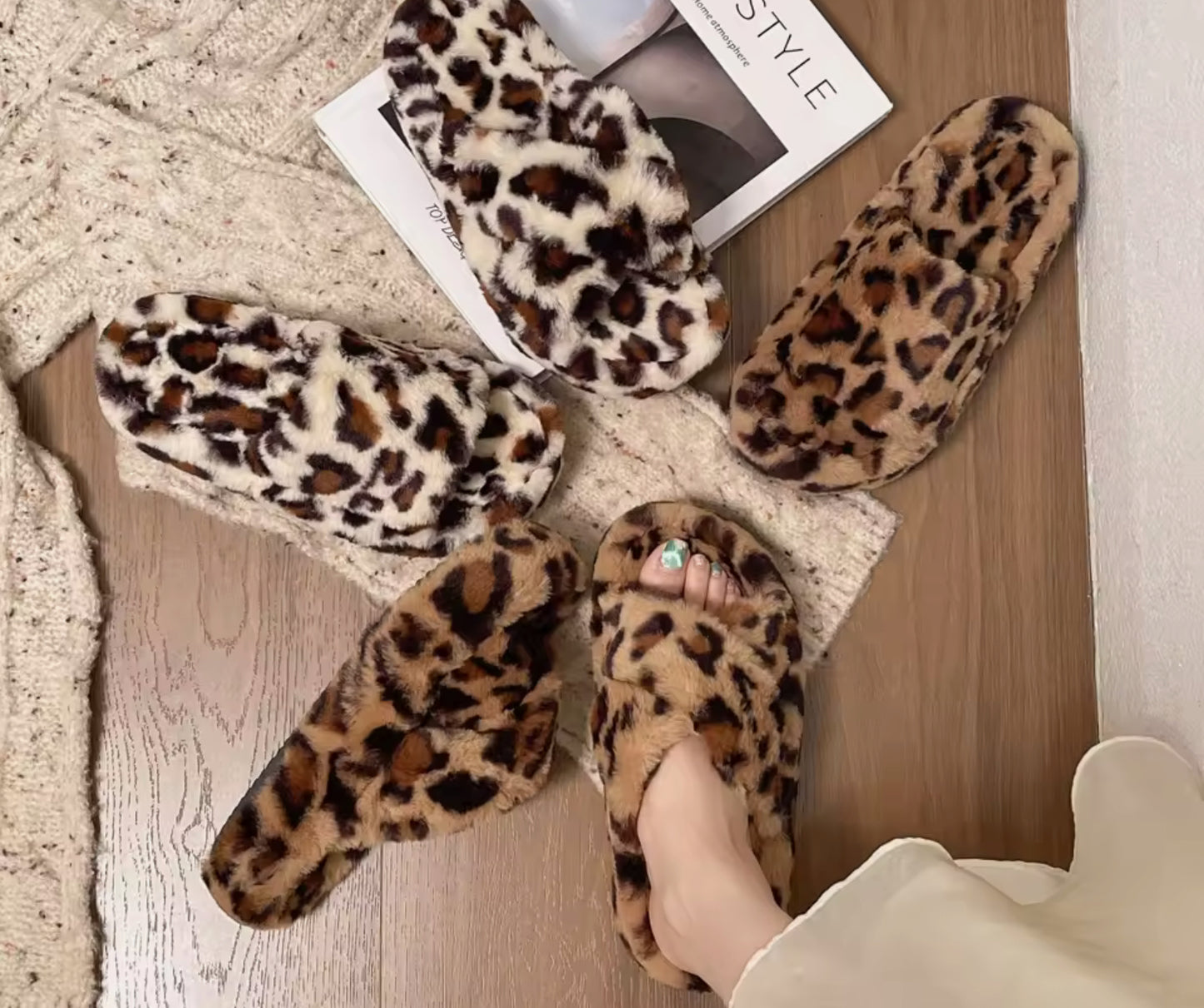 Pear Aeneas women's leopard faux fur slippers arranged on a cozy surface with a stylish magazine.