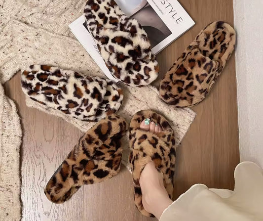 Pear Aeneas women's leopard faux fur slippers arranged on a cozy surface with a stylish magazine.